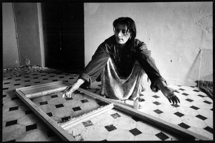 Nasifa répare les vitres d'une des portes fenêtres de son appartement. Les appartements étant dans un état de délabrement et d'insalubrité avancés.